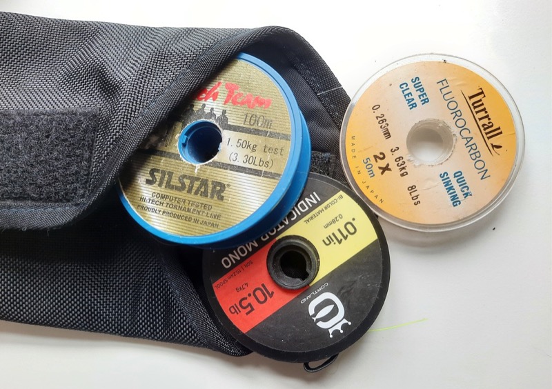 Three reels of fishing line appearing out of a bag