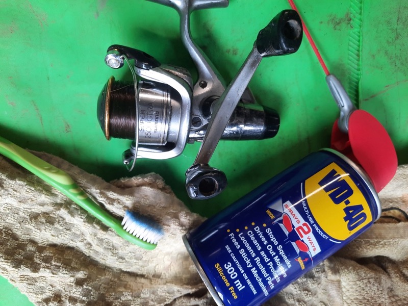 Close up of a fishing rod on a green background with a WD-40 can